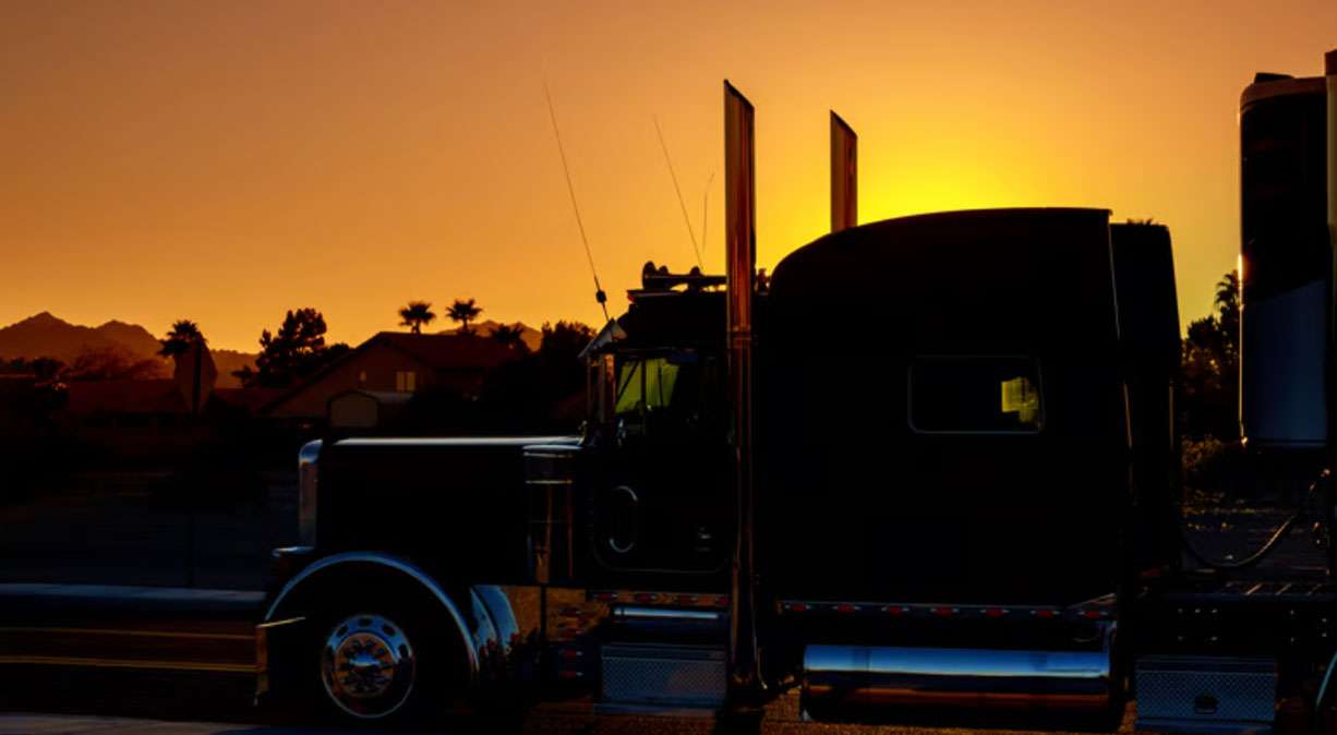 Semi-truck silhouette at sunset representing freight shipping and logistics in Milwaukee.